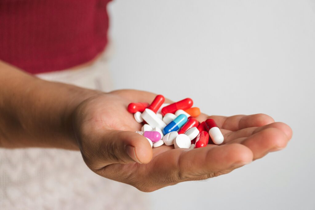 Close-up of a hand holding various colorful pills and capsules.